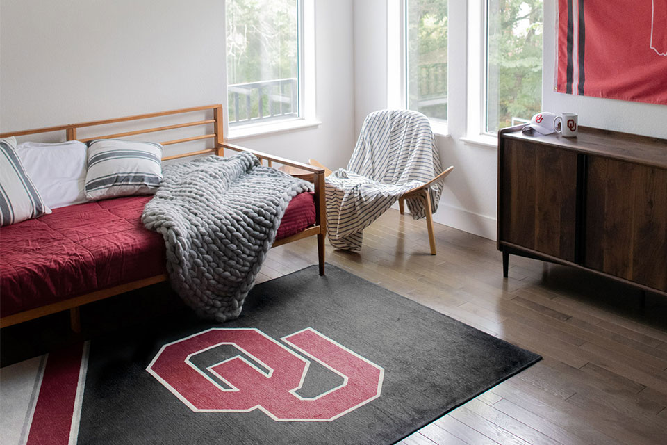 college logo rug in dorm room by bed