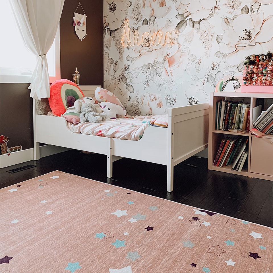 Pink star rug with floral wallpaper and white bed in girls bedroom