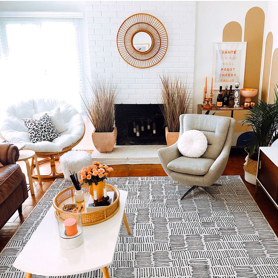 Black and white rug with grid lines in living room with white coffee table grey chair and brown leather couch