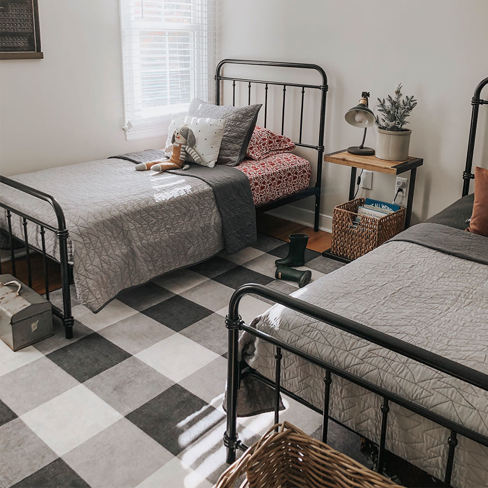 Buffalo plaid black and white rug between two twin beds in kids room