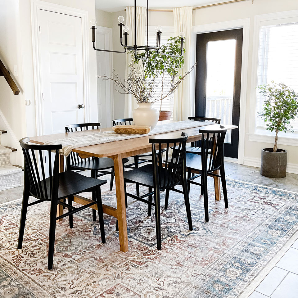 Farmhouse rug under wood dining table with 6 black chairs