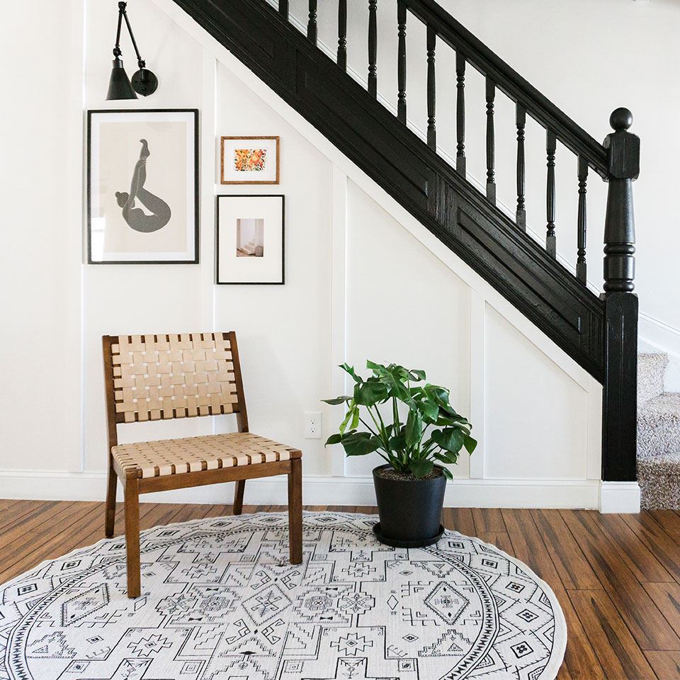 Black and white round rug in the entryway under the stairs