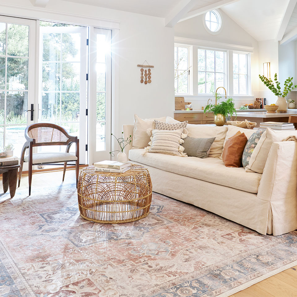 Cream couch with rattan coffee table and coral farmhouse rug in the living room