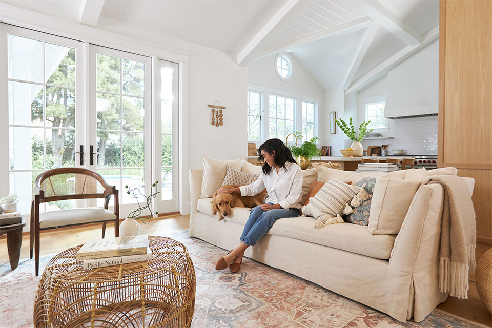 Woman with brown dog on cream couch with coral farmhouse rug in the living room