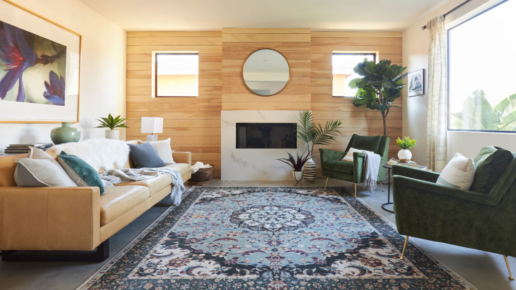 Persian rug in living room with brown leather couch and green accent chairs
