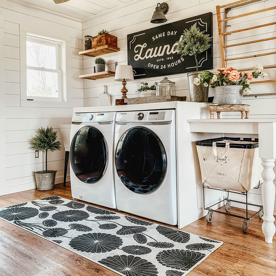 Black and white floral rug with washing machine in laundry room.