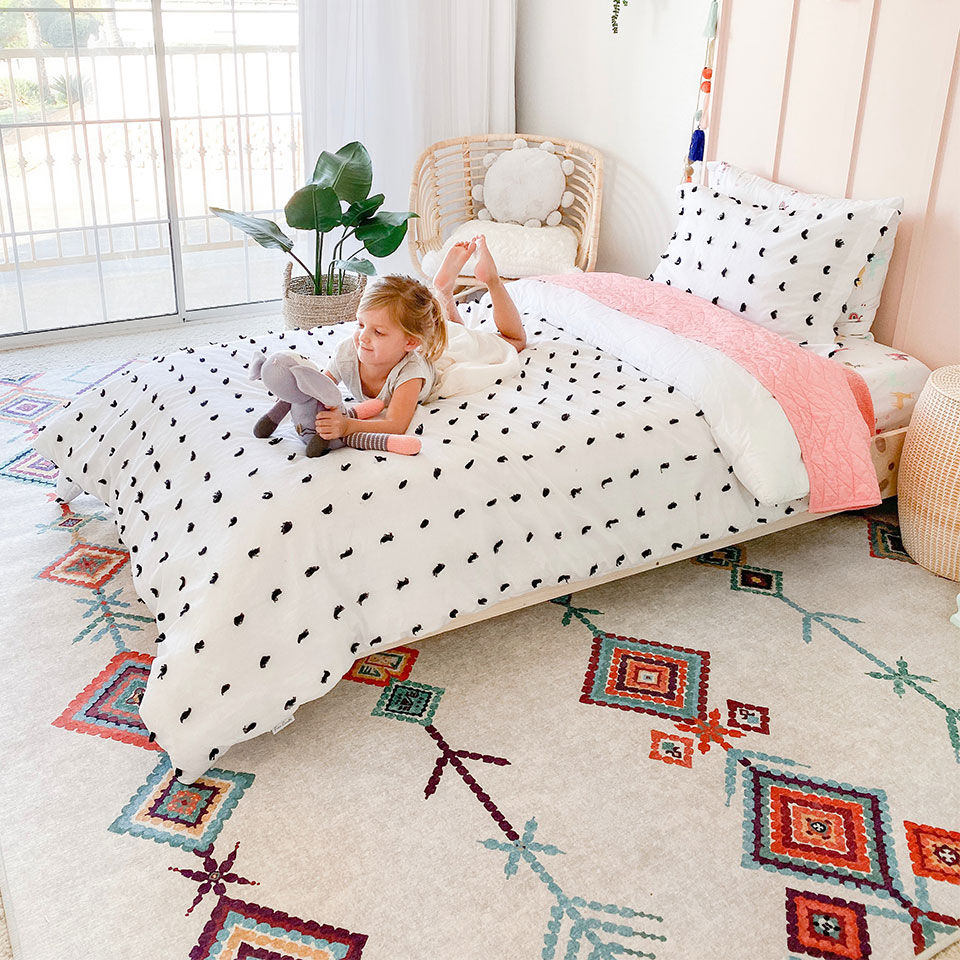 Colorful diamond rug and pink and white bed in girls bedroom