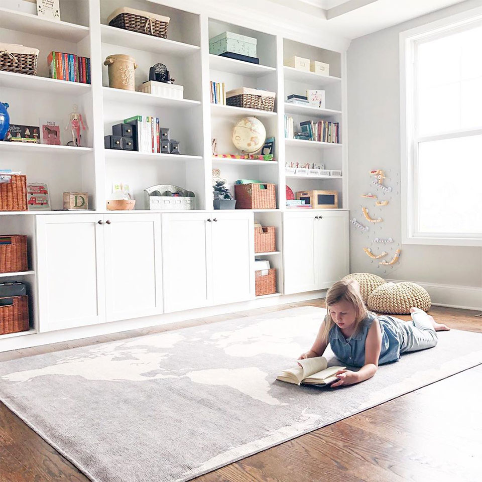 Girl reading on grey world map rug in homeschool
