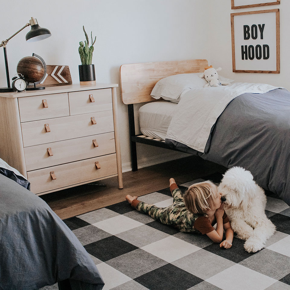 Black and white checkered rug in boys room with white dog