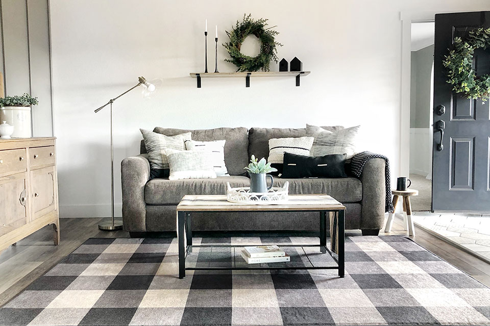 Black and white checkered rug with grey couch in living room