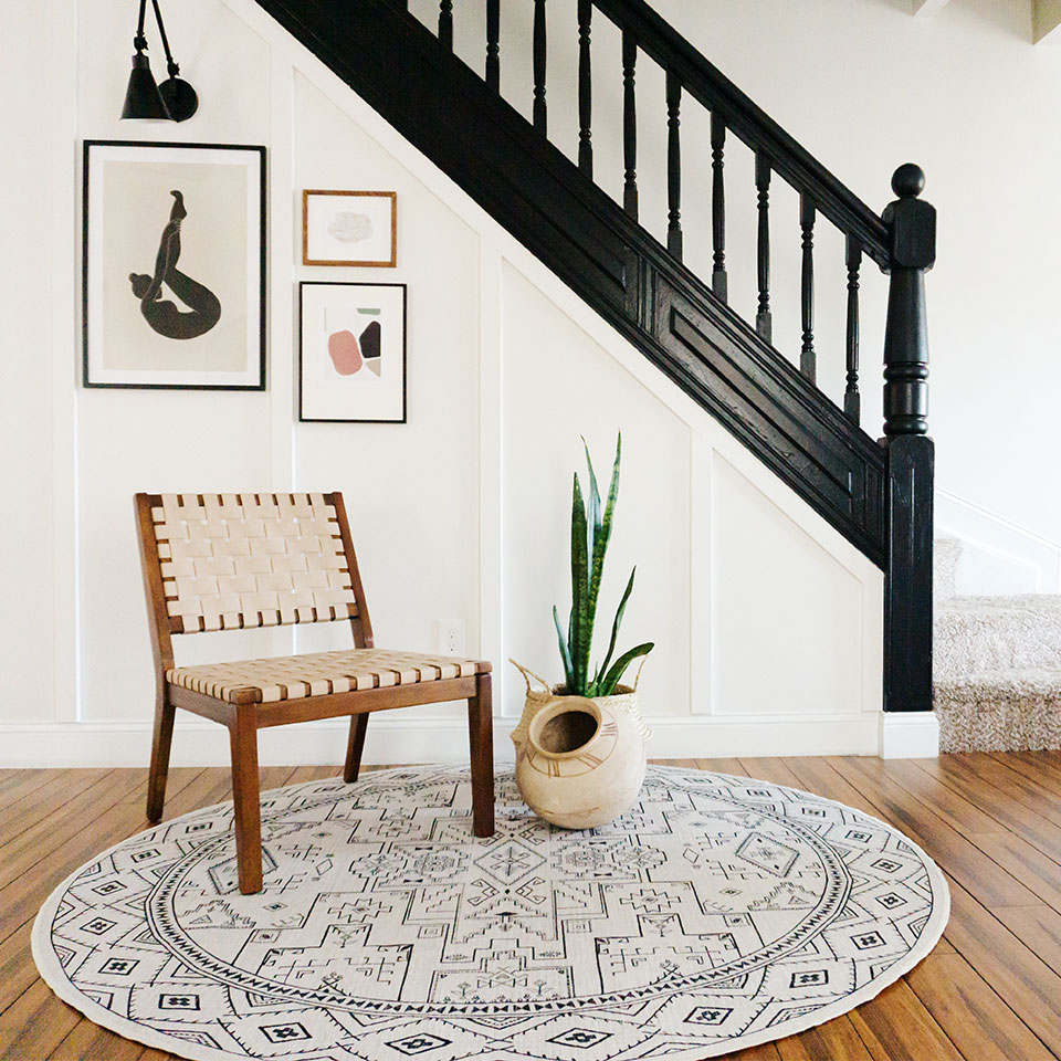 Black and white geometric round rug under the staircase with chair and plant