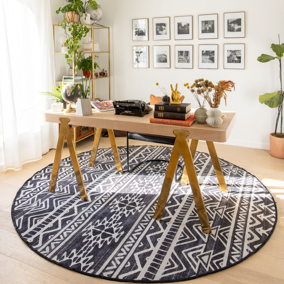Black and white round rug with wooden table, shelves and plants in office