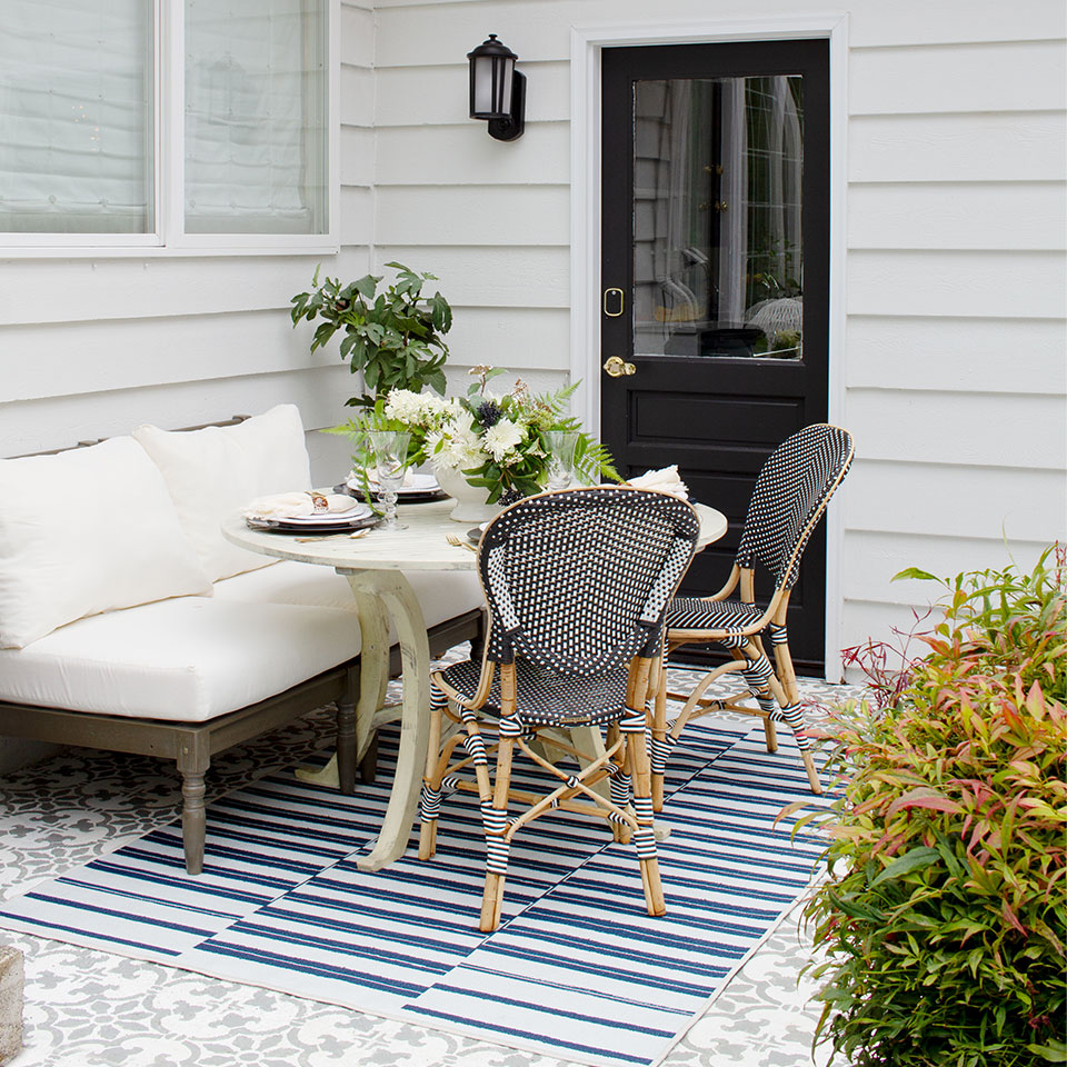 Blue and white striped outdoor rug with white couch and plants