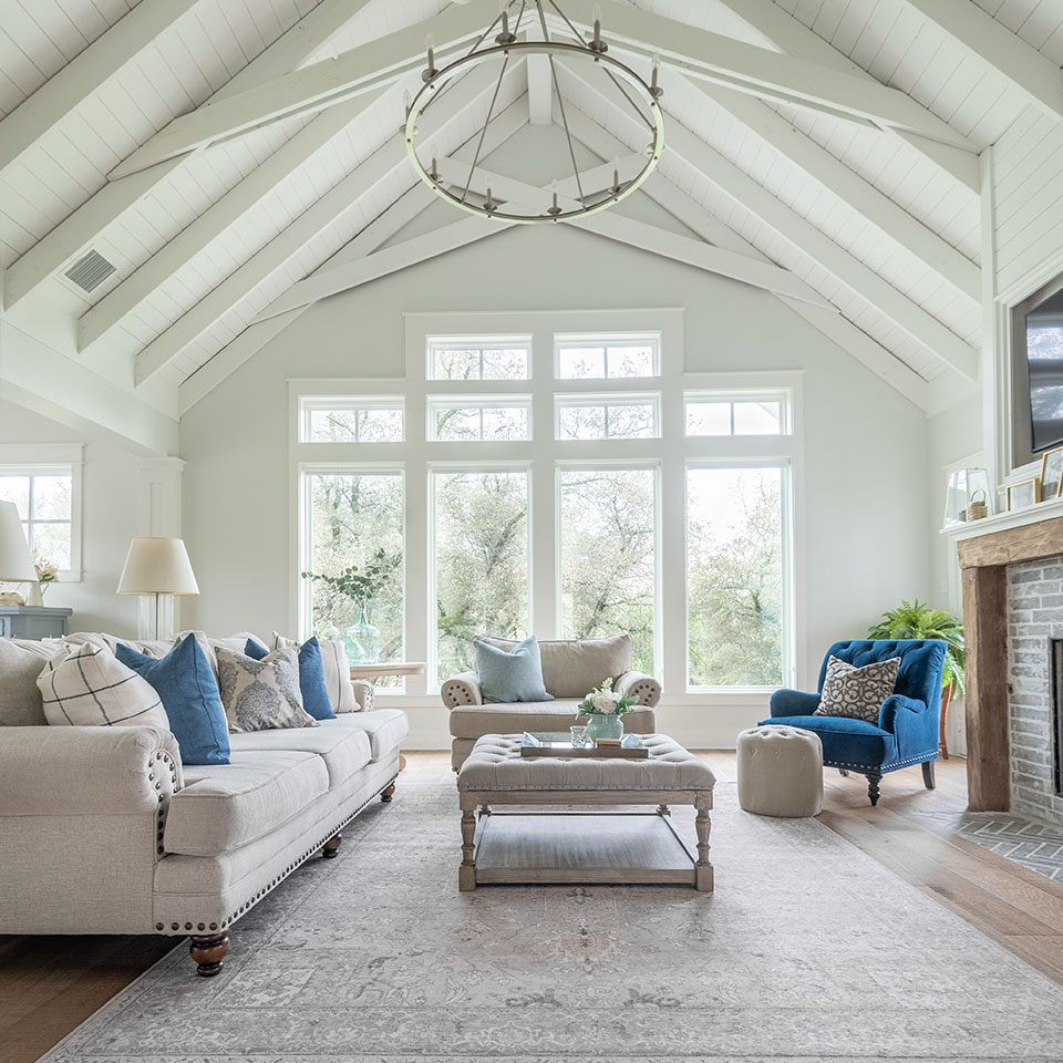 High ceiling with wooden beams in living room with cream and blue couch and grey Persian rug.jpg