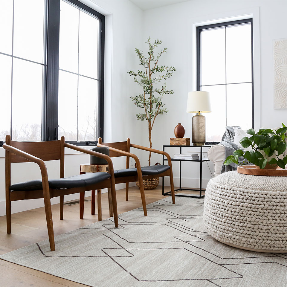Midcentury modern black and brown chairs with natural rug woven ottoman and plants in the living room