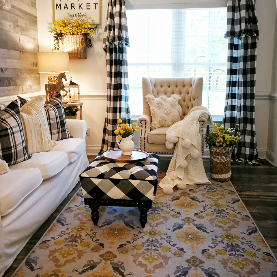 Yellow floral rug with black and white plaid curtains and white couch in living room