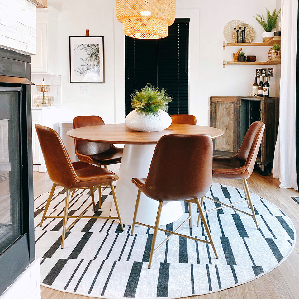 black and white striped round rug with round table and leather chairs in dining room