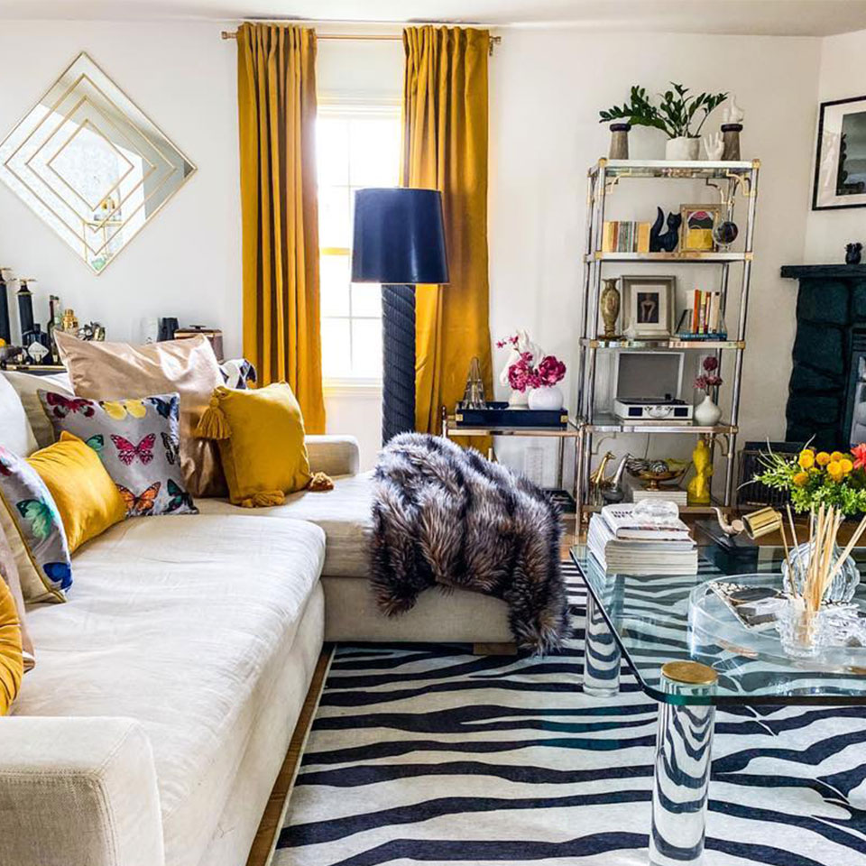 Black and white zebra rug in living room with yellow pillows and cream couch