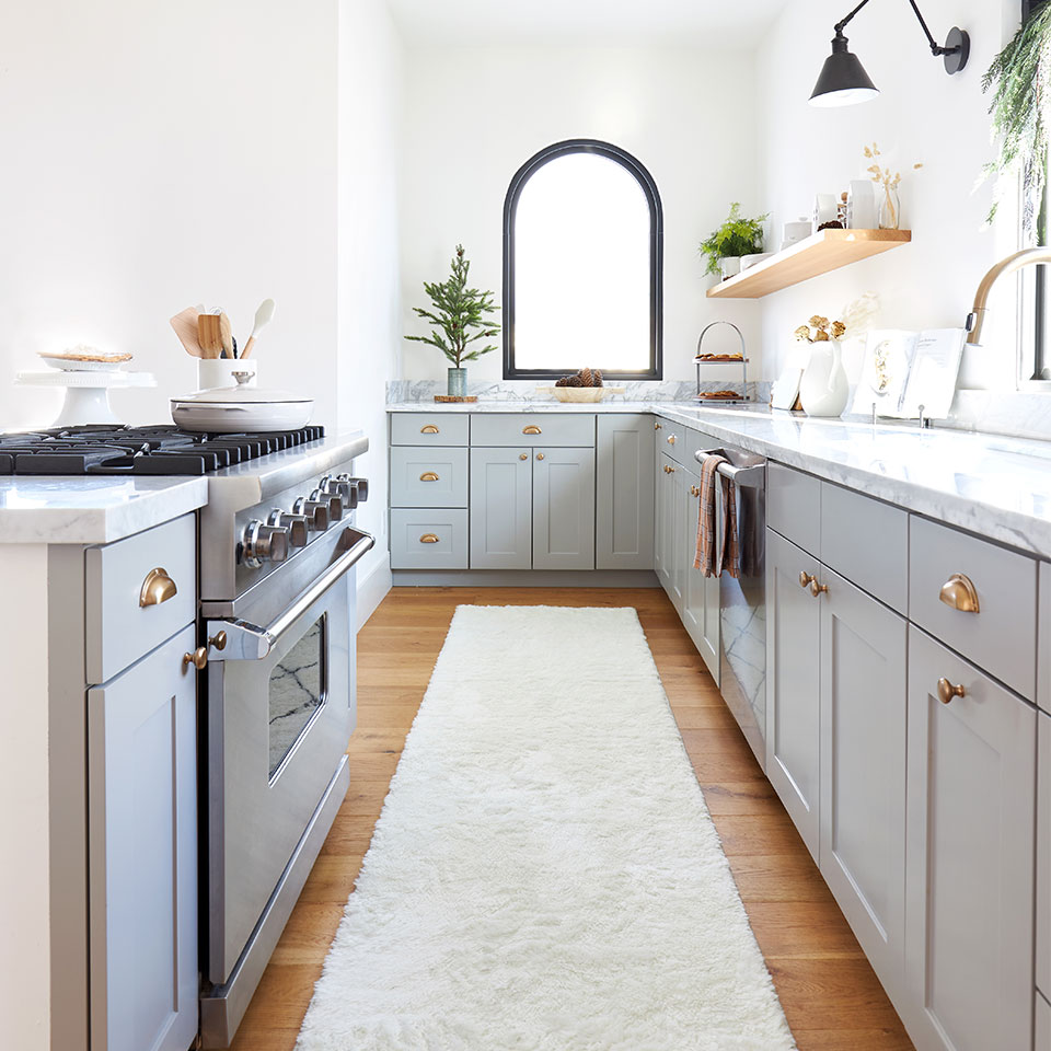 White plush rug in white kitchen with grey cabinet gold handles and marble counter.