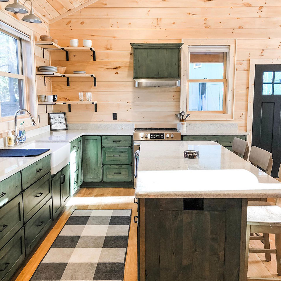 Farmhouse kitchen with black and white plaid rug and green cabinet