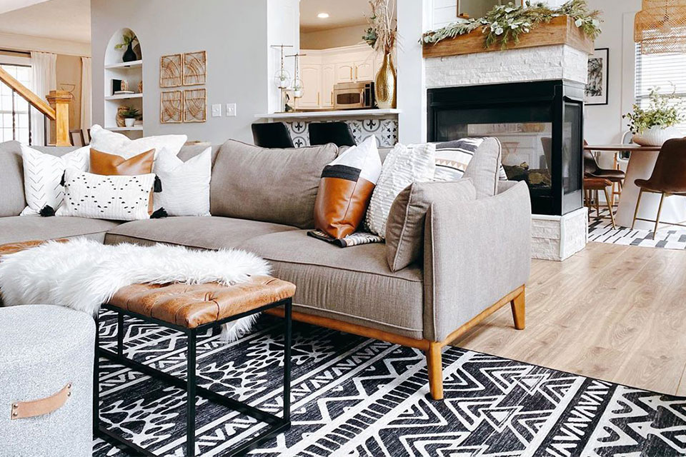 Black and white geometric rug with grey couch and leather bench in living room