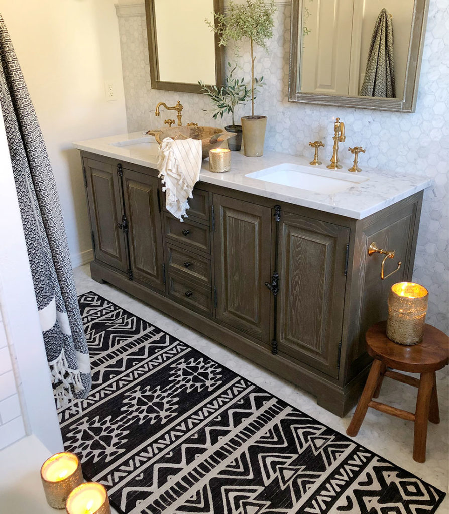 Black and white runner rug with marble counter and wood vanity with candles in bathroom