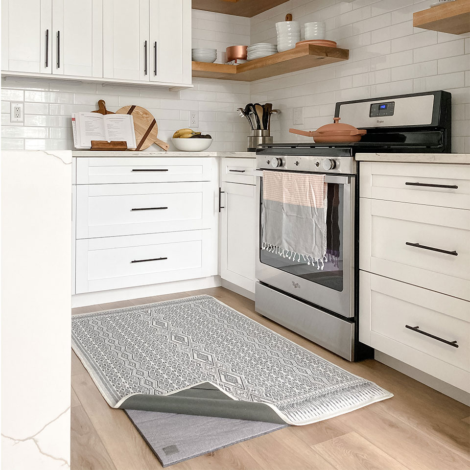 Thick rug pad under black and white rug in white kitchen