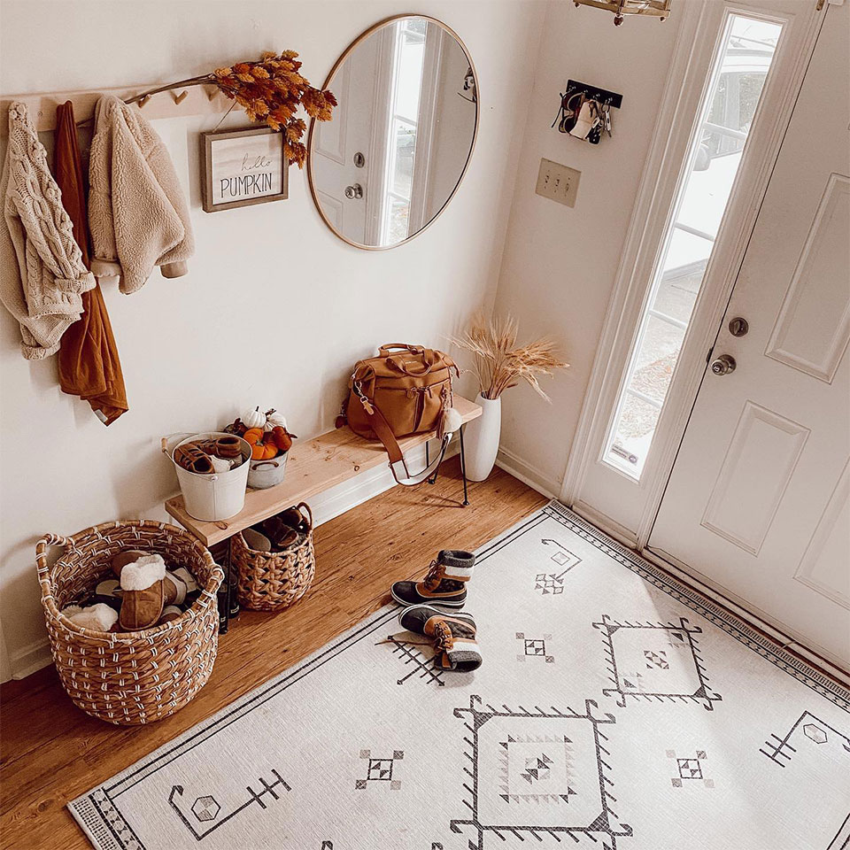 black and white geometric rug with rattan baskets and pumpkin in entryway