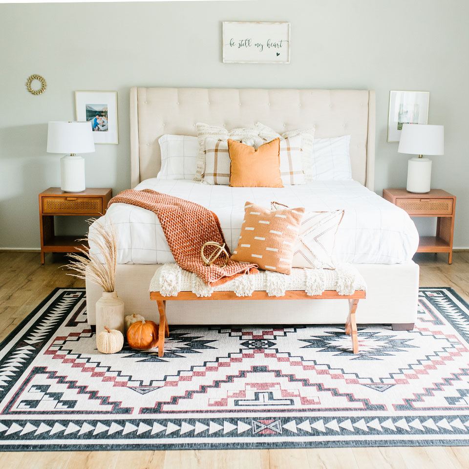 geometric black and brown rug under queen bed with pumpkin and brown pillow