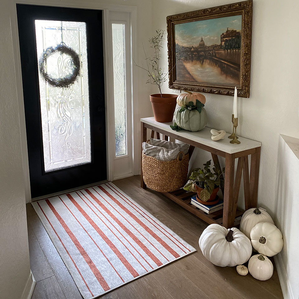 orange stripe rug with white pumpkin with console in entryway
