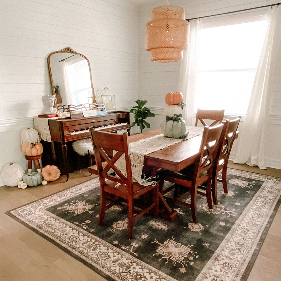 Farmhouse dining room rug with wood table and cream runner and pumpkin decor