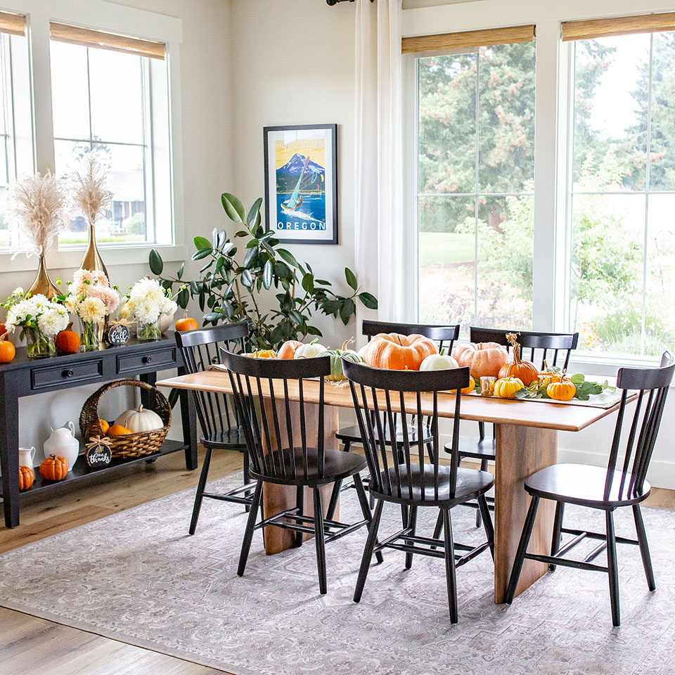 Grey rug under wood dining table with pumpkin decor in dining room