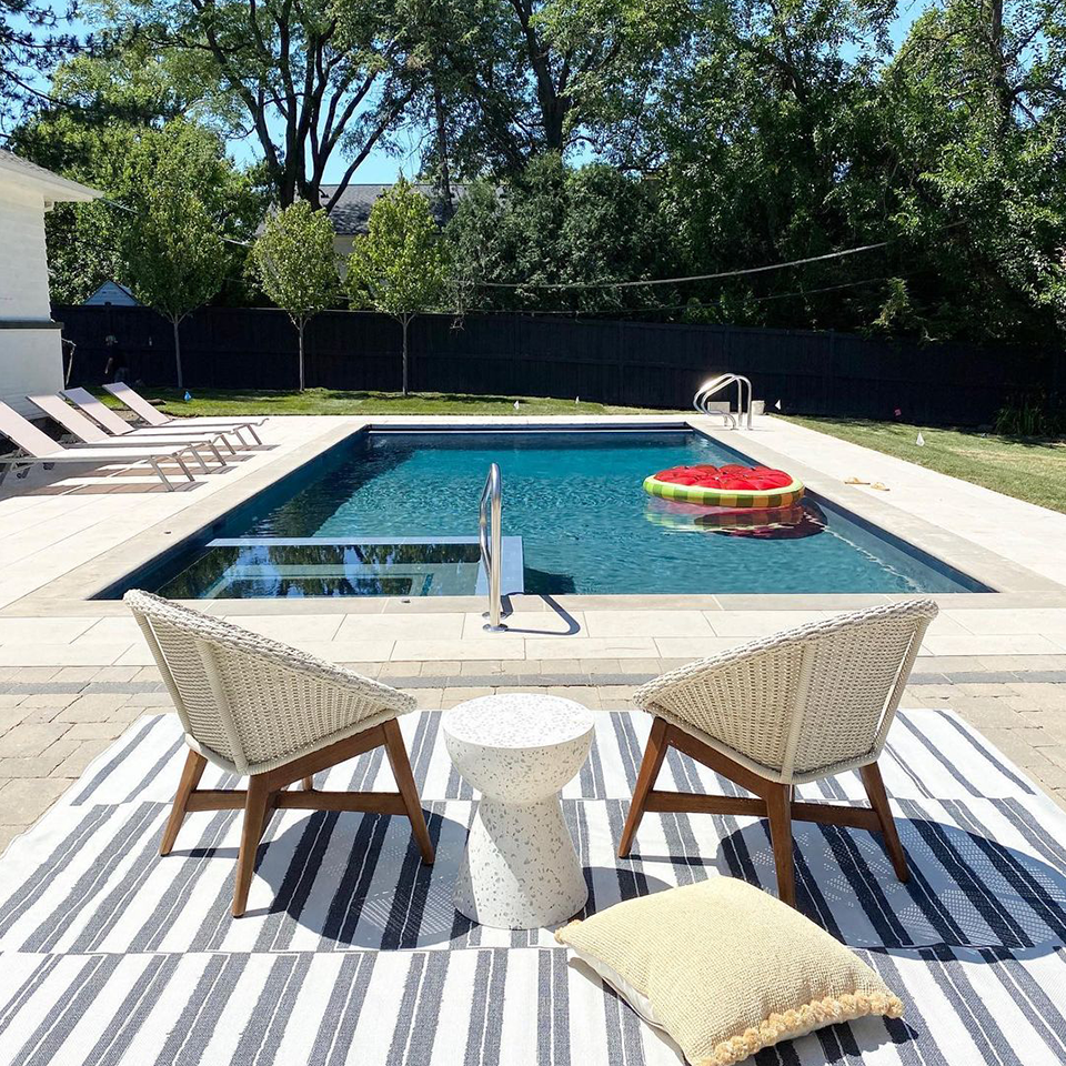 blue and white striped outdoor rug by pool with patio furniture