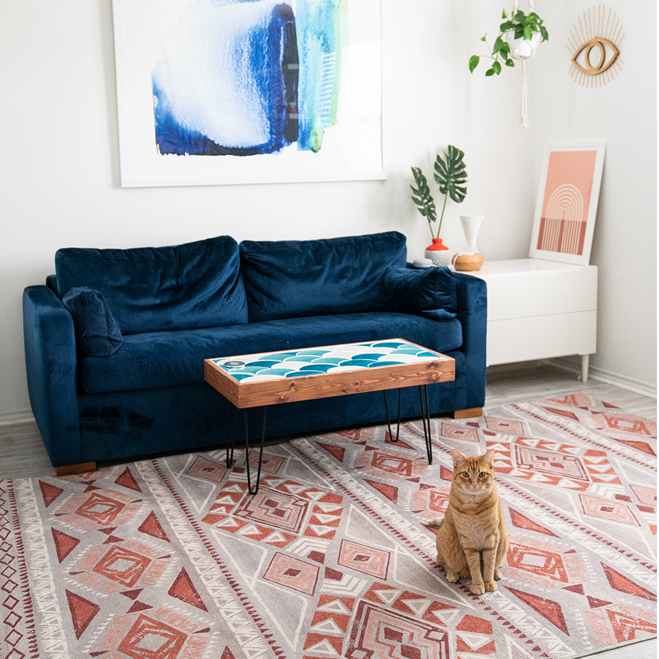 coral geometric rug in living room with blue velvet sofa