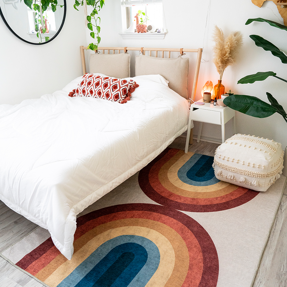 rainbow rug in boho bedroom with white bed and plants