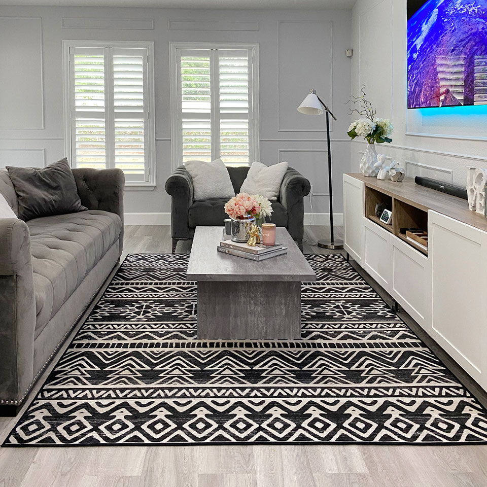 Black and white geometric rug with grey floor and grey couch in living room