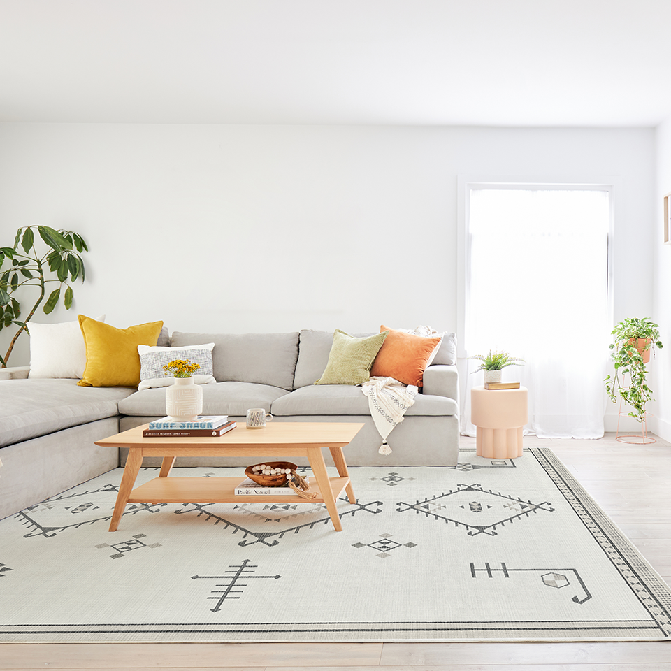 grey living room with boho rug and yellow throw pillow