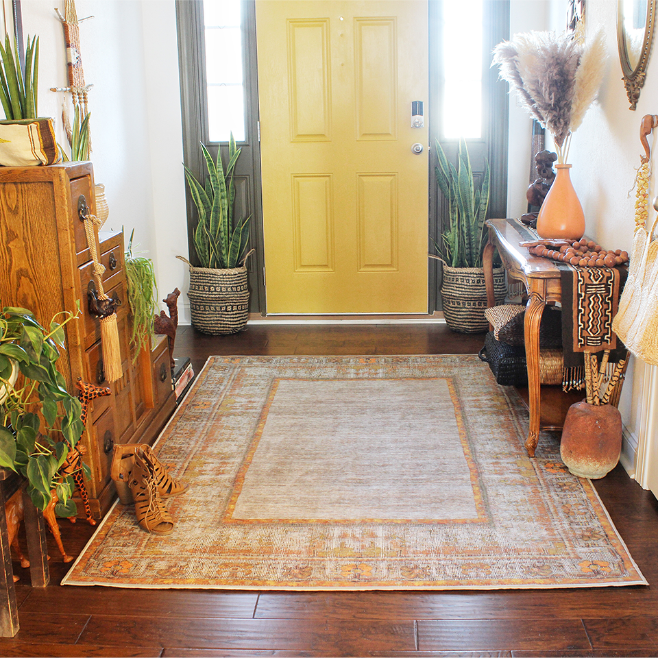 grey and yellow front door in entry with plants and yellow orange rug