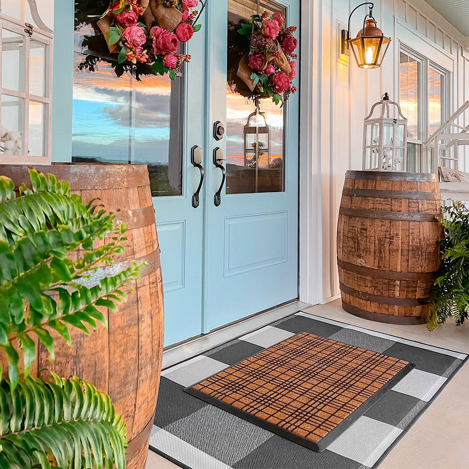 Spring themed doorway with checkered coir doormat on black and white plaid rug blue door and floral wreath