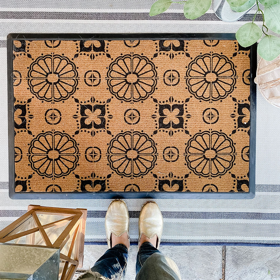 Top shot of coir doormat with floral pattern with gold shoes