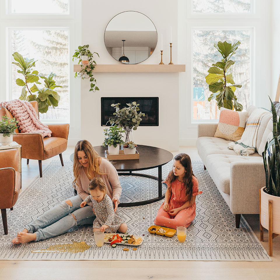 Woman and two kids eating snacks and spilling liquid on black and white geometric rug in the living room.jpg