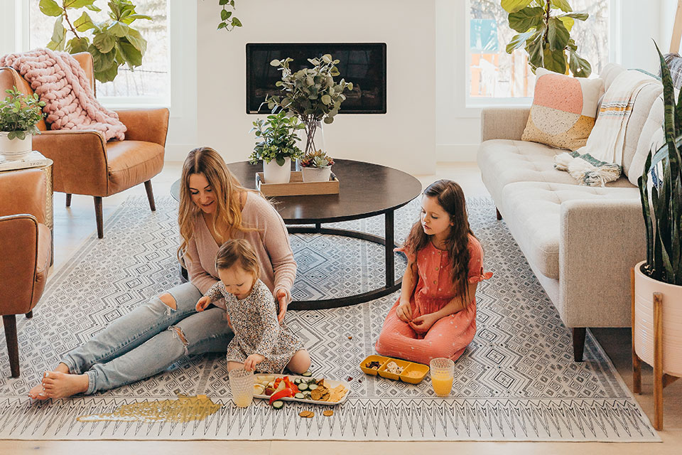 Woman and two kids spilling beverage on black and white rug in the living room