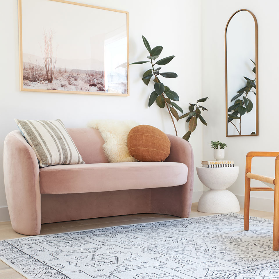 small living room with black and white boho rug and pink sofa