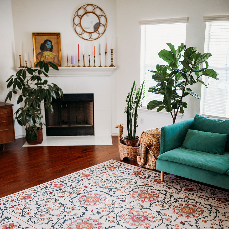 spring floral rug in living room with fireplace and green velvet sofa