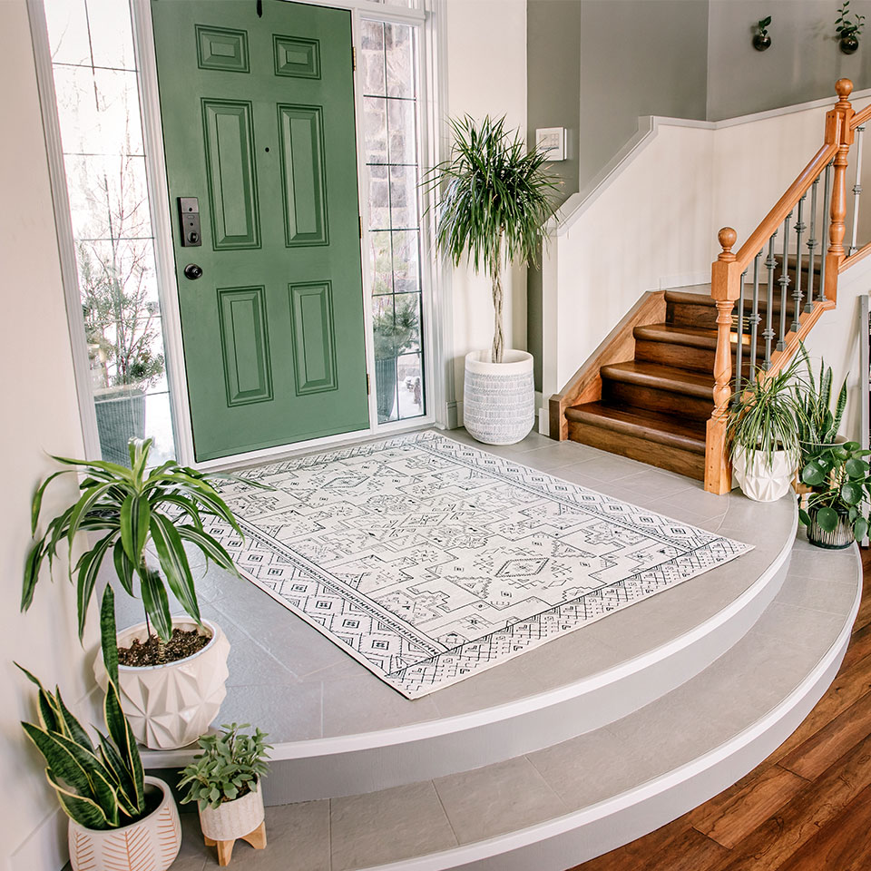 bright green front door with black and white boho rug and plants in entryway foyer