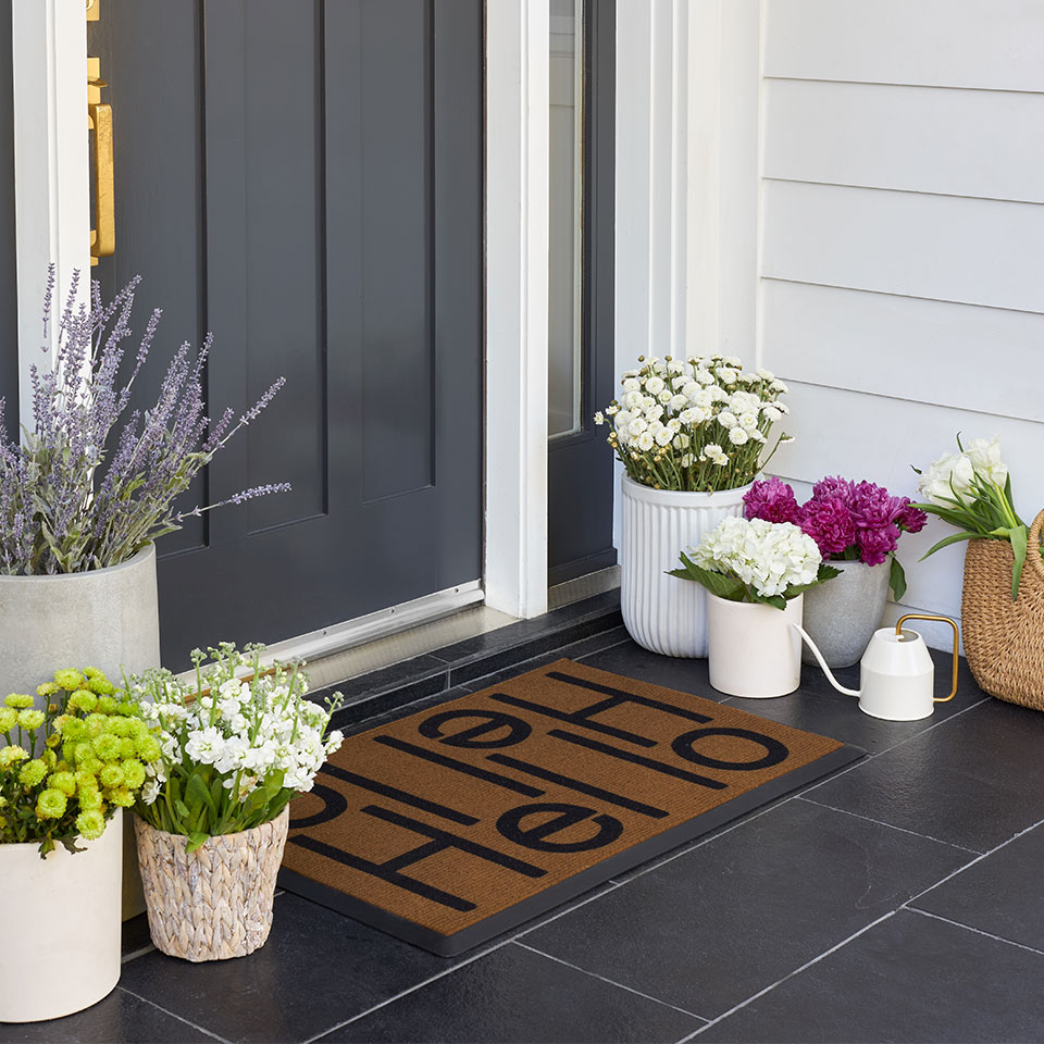 welcome doormat by navy front door with plants