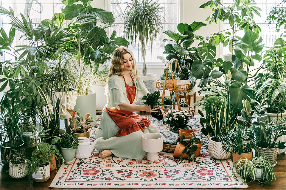 woman sitting on colorful floral spring rug tending to her plants