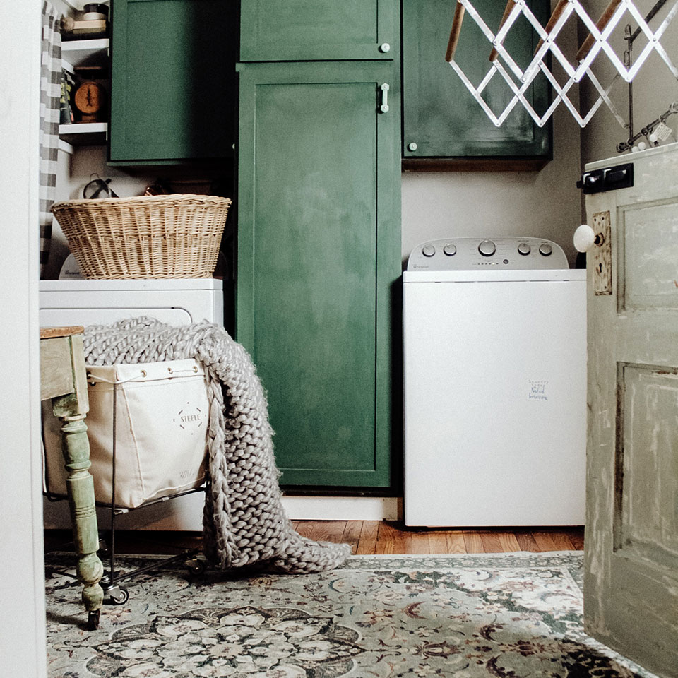 green persian rug in laundry room with painted green cabinets