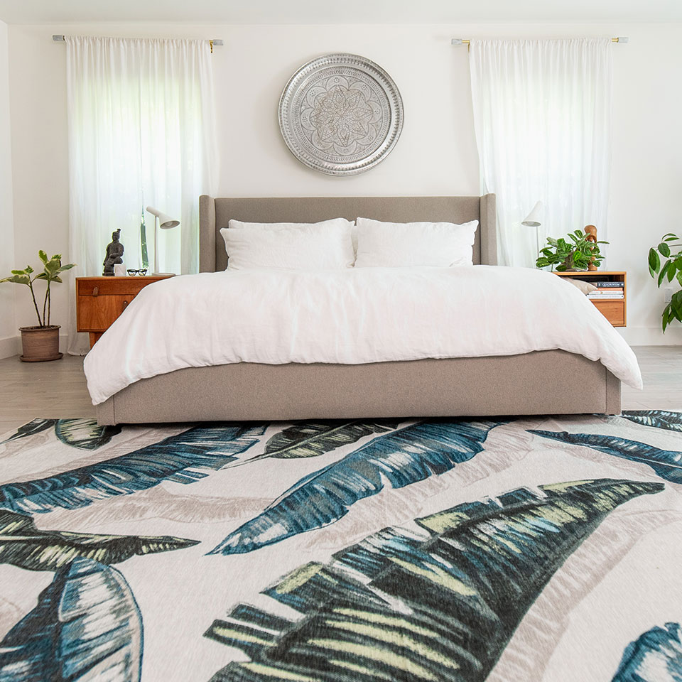 neutral bedroom with blue and green palm leaf rug