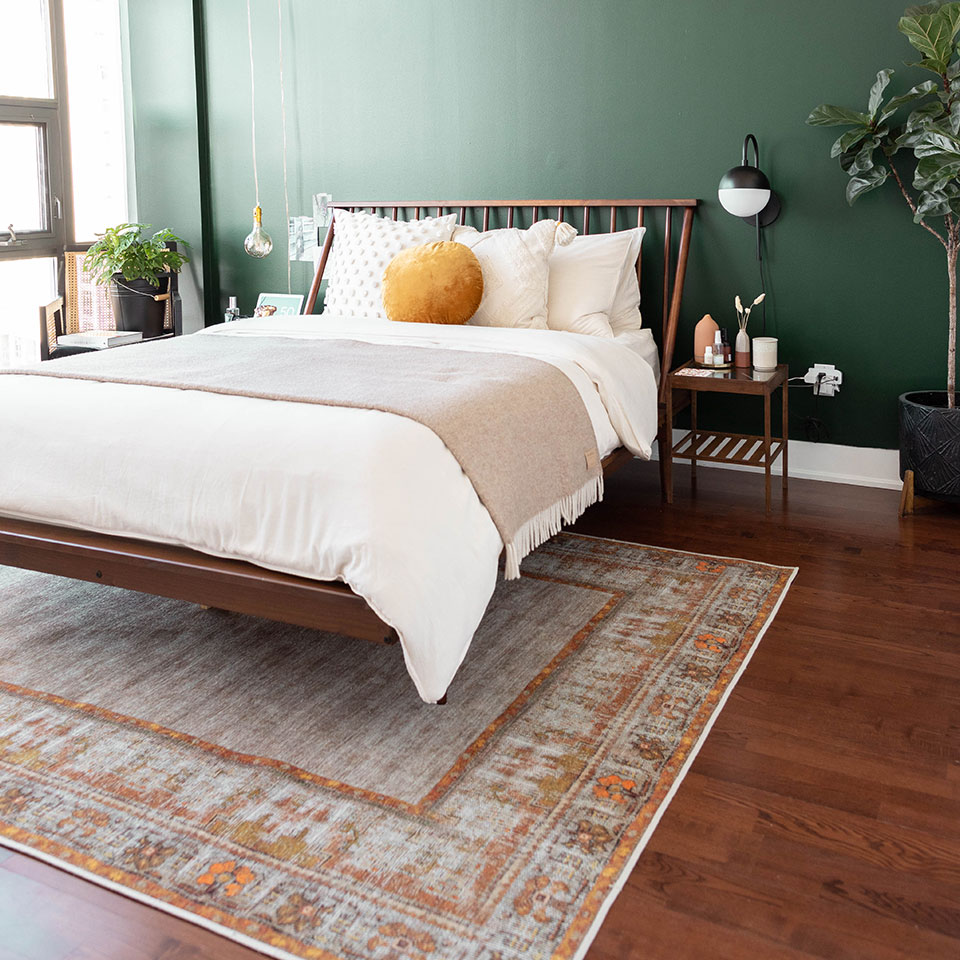 orange rug in bedroom with green wall